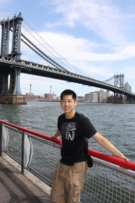 Jeff Kao standing at a waterfront railing with the Manhattan Bridge behind him